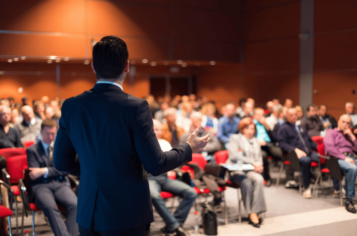 A speaker address the crowd at a dental conference. 